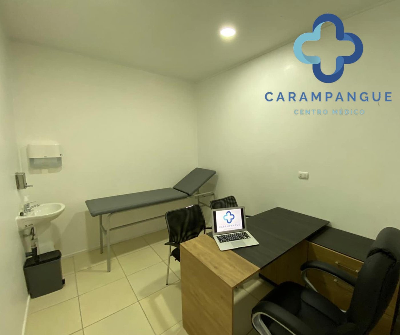 Box de atención médica con camilla, escritorio y lavamanos